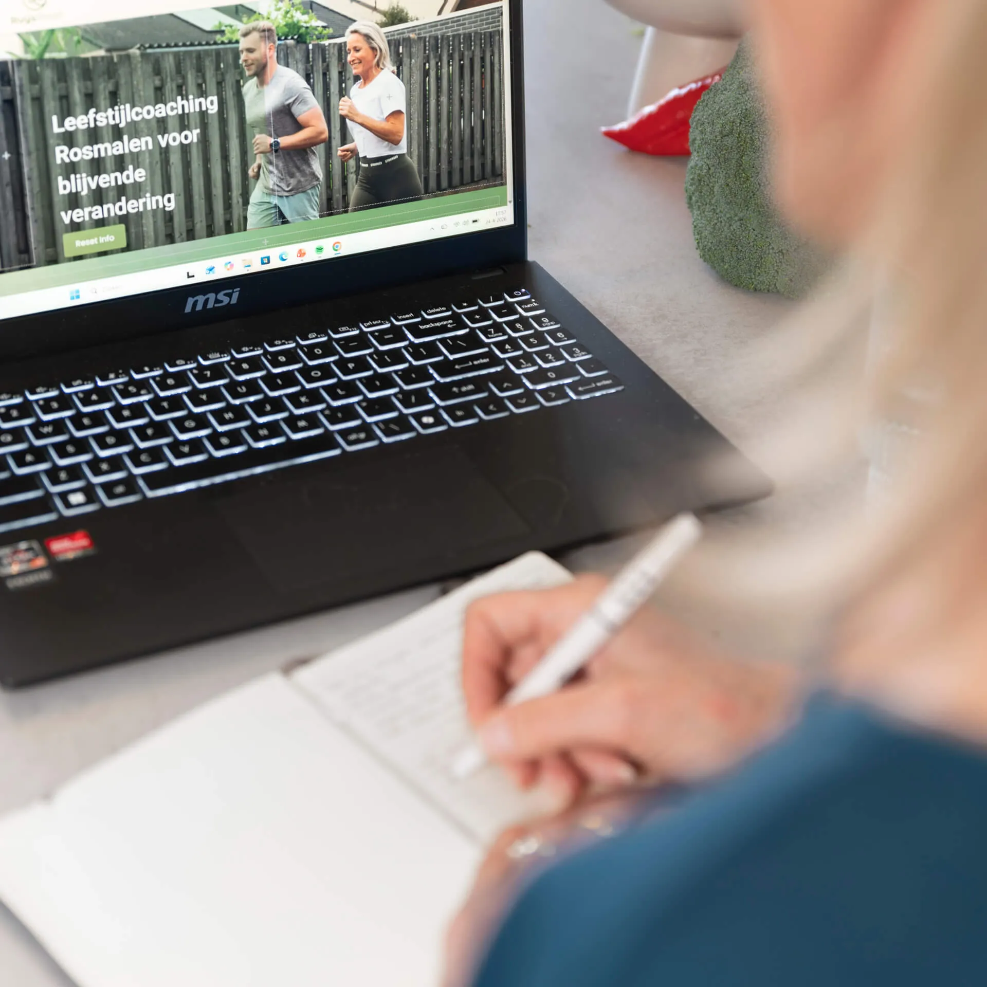 Iemand maakt aantekeningen naast een laptop