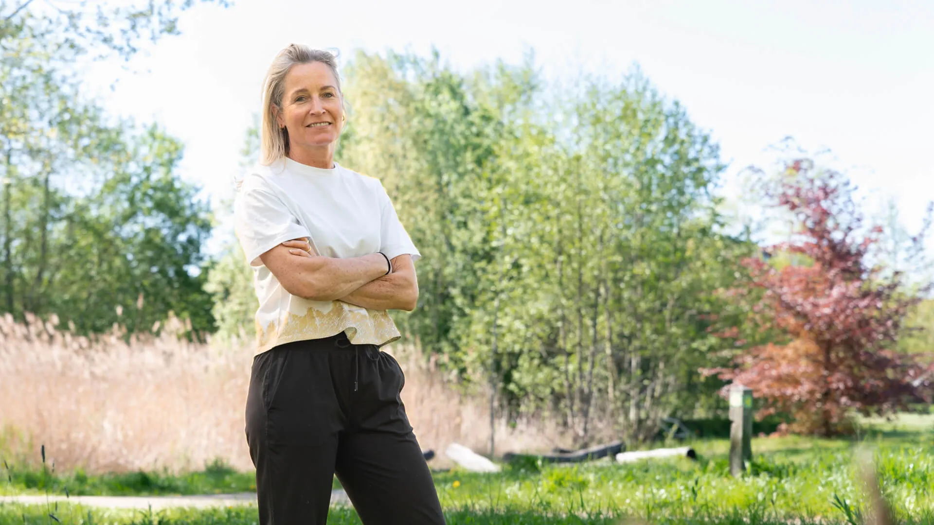 Edith staat met haar armen over elkaar in de natuur bij een rietveld