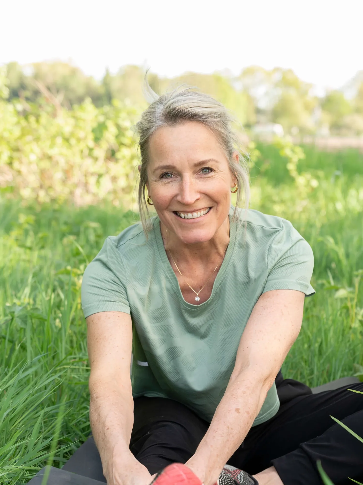 Edith zit lachend op een mat in het gras