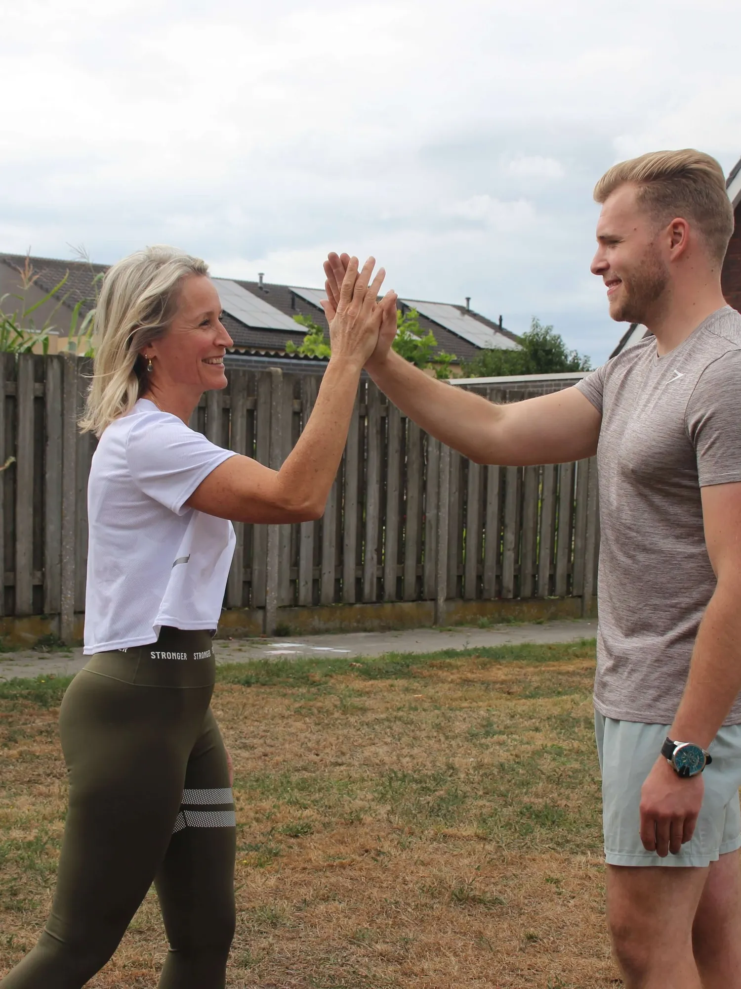 Edith geeft een cliënt een high five na een buitentraining in de tuin